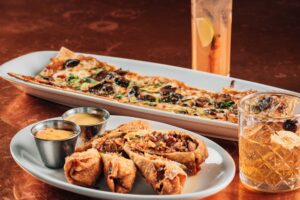 photo of smoked reuben egg rolls, french onion flatbread and drinks